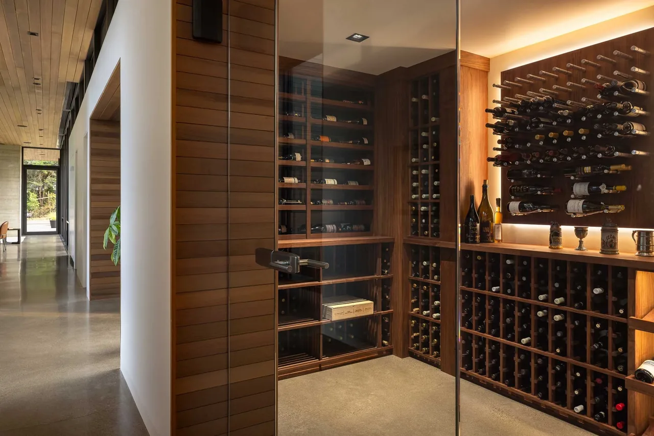 Wine cellar with wood racks and glass door inside a contemporary residence named Evening Sky.