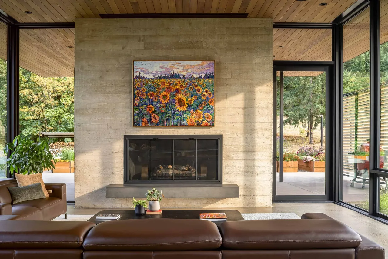 Living room features a concrete fireplace wall with black-framed glass doors and leather seating, opening to an outdoor space with glass walls.