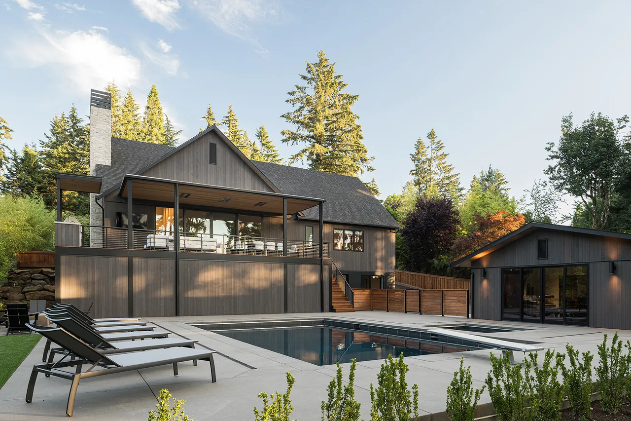 Fernwood House exterior with vertical wood siding, steep roof pitch, and pool area including lounge chairs.