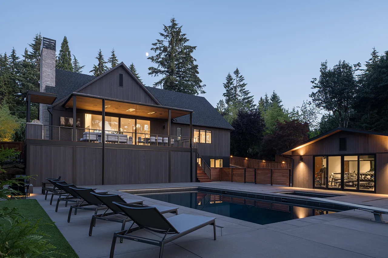 Fernwood House features vertical wood siding, a covered deck, and a concrete pool deck with lounge chairs.