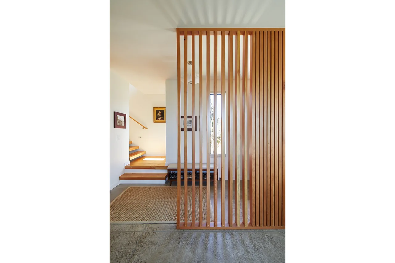 View of a staircase area featuring a wood slat divider and concrete flooring at Sahhali Shores Shelter.
