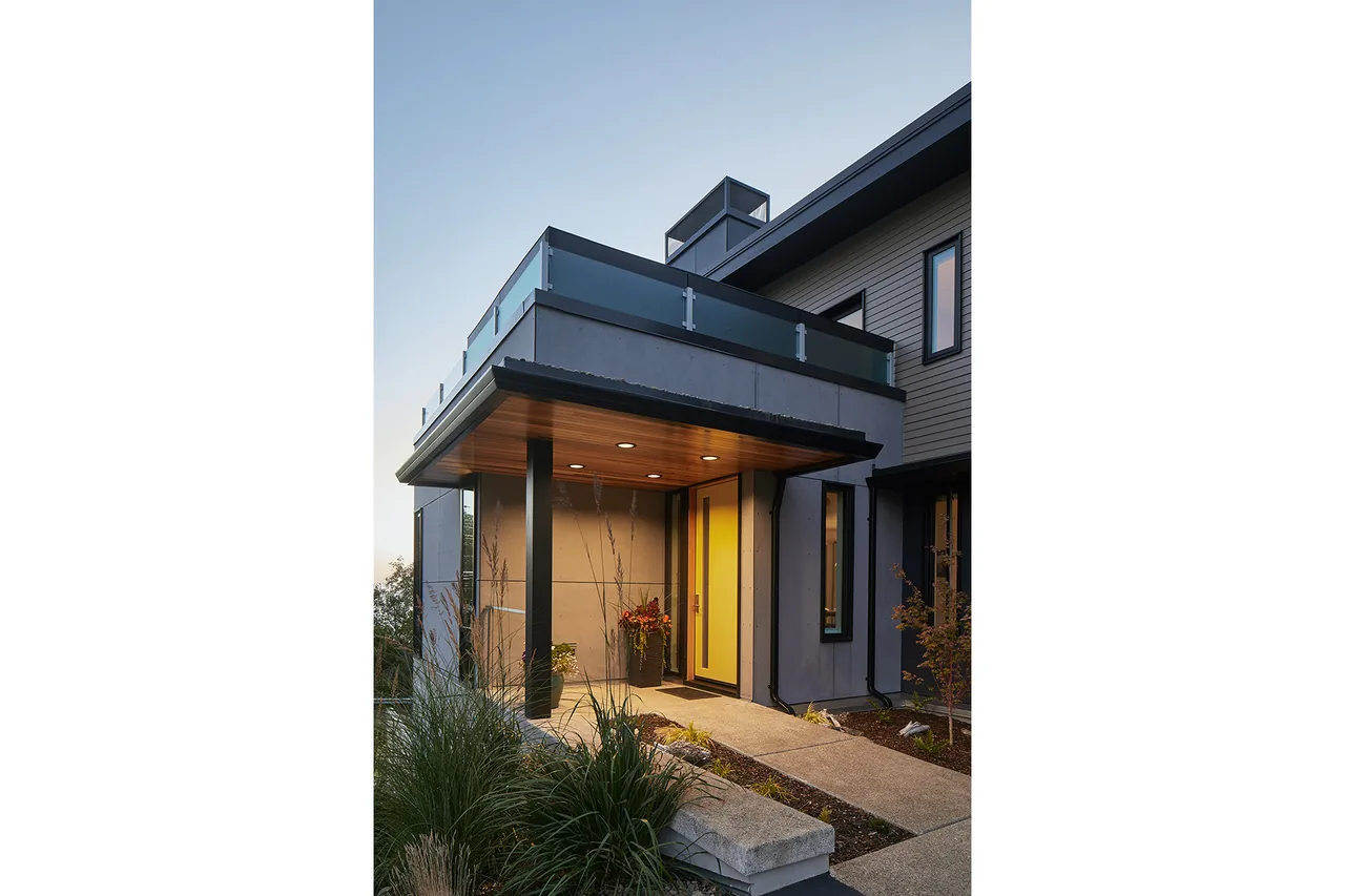 The Sahhali Shores Shelter features a covered entry porch and glass balcony railing on a multi-story house.