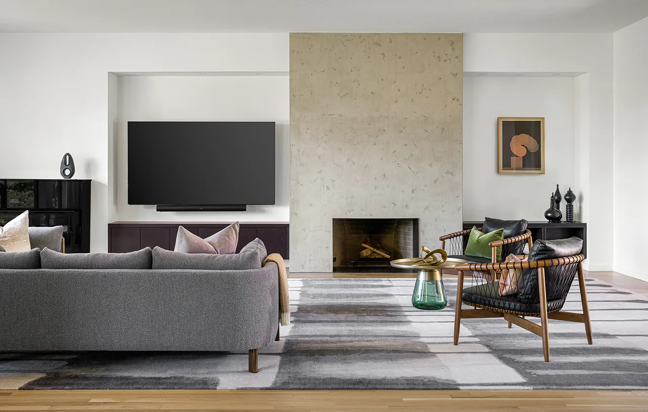 Living room with a floor-to-ceiling concrete fireplace, gray sofa, and wood furniture with an abstract art piece on the wall.