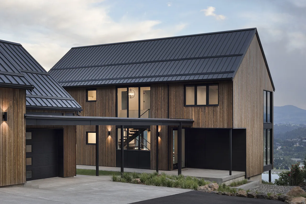 Hilltop House features black steel gable roofs, vertical wood siding, and a covered walkway linking main and garage.