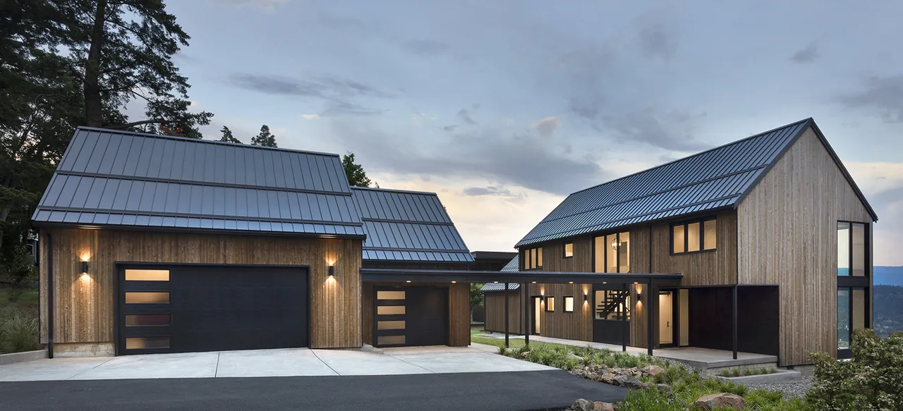 Hilltop House features rustic wood siding and metal gable roofs with a covered walkway connecting the detached garage and main house.