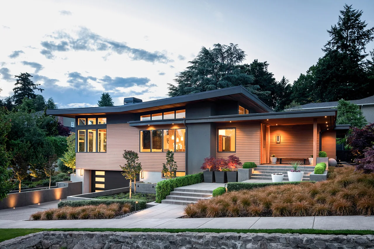 Highlands Loop Residence is a single-story modern home with large windows, overhanging eaves, and lit landscaping in Portland.