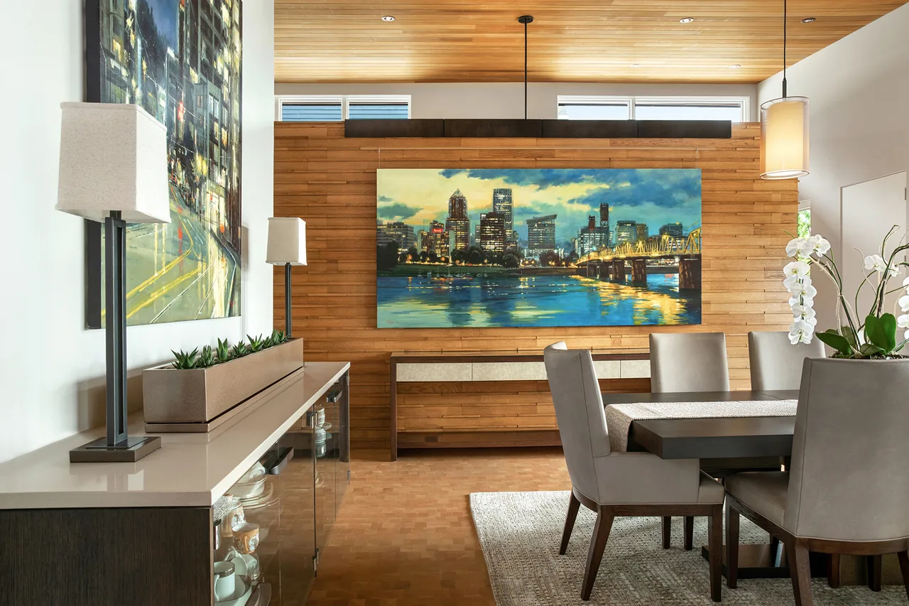 Dining area with a wood-paneled wall featuring cityscape artwork and beige upholstered chairs around a wooden table.
