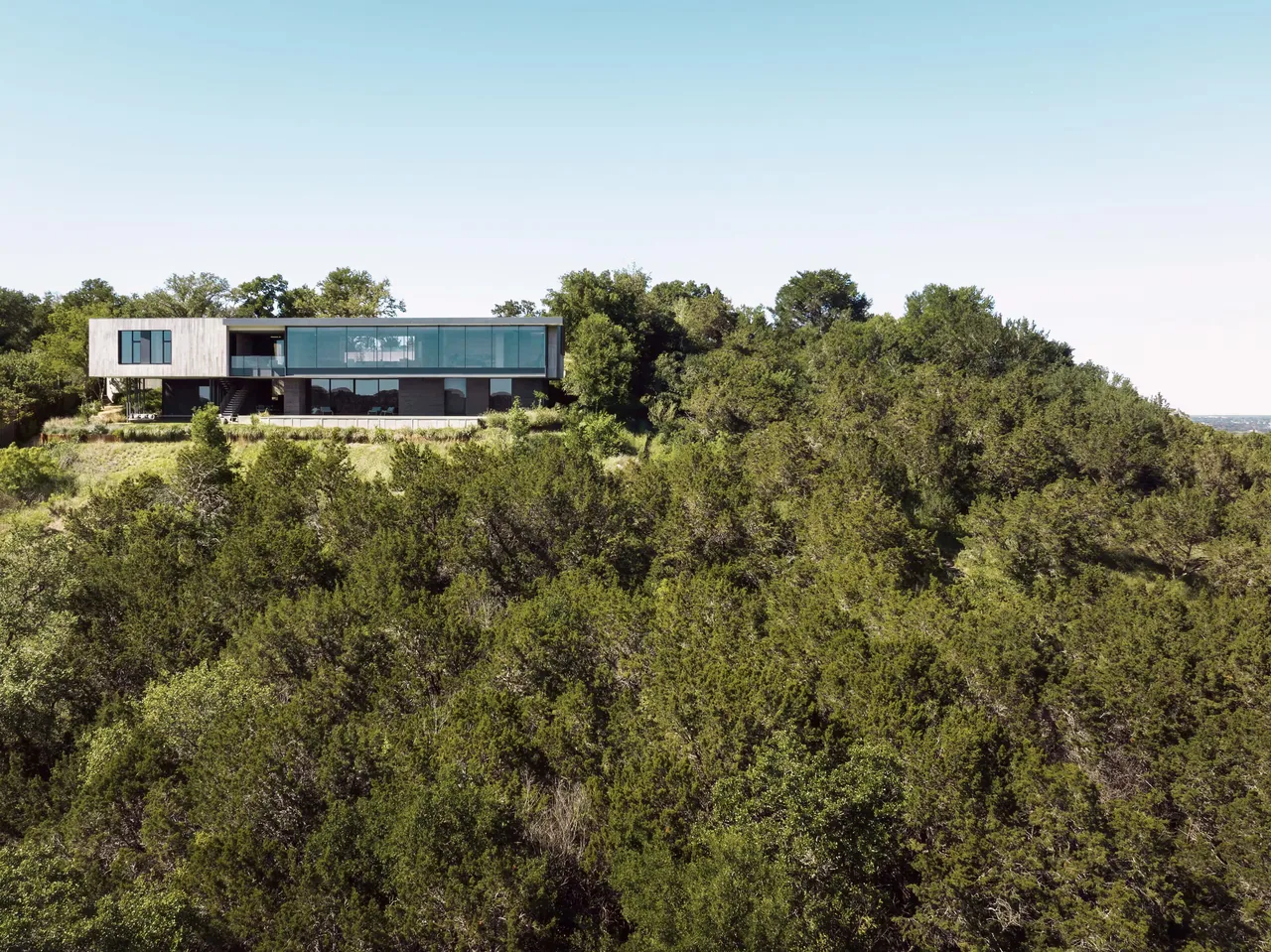 The Barton Hills Residence by Alterstudio features expansive glass walls and is set on a wooded hillside in Austin.