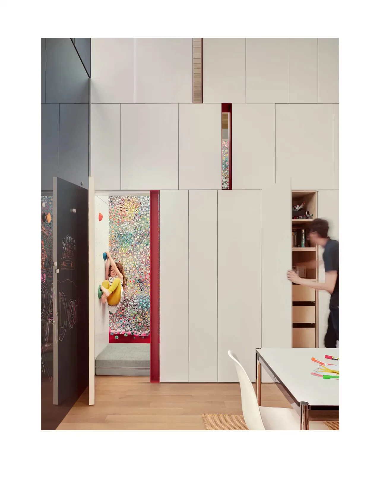 Room with built-in cabinetry and a small climbing area with colorful holds integrated in a wall niche.