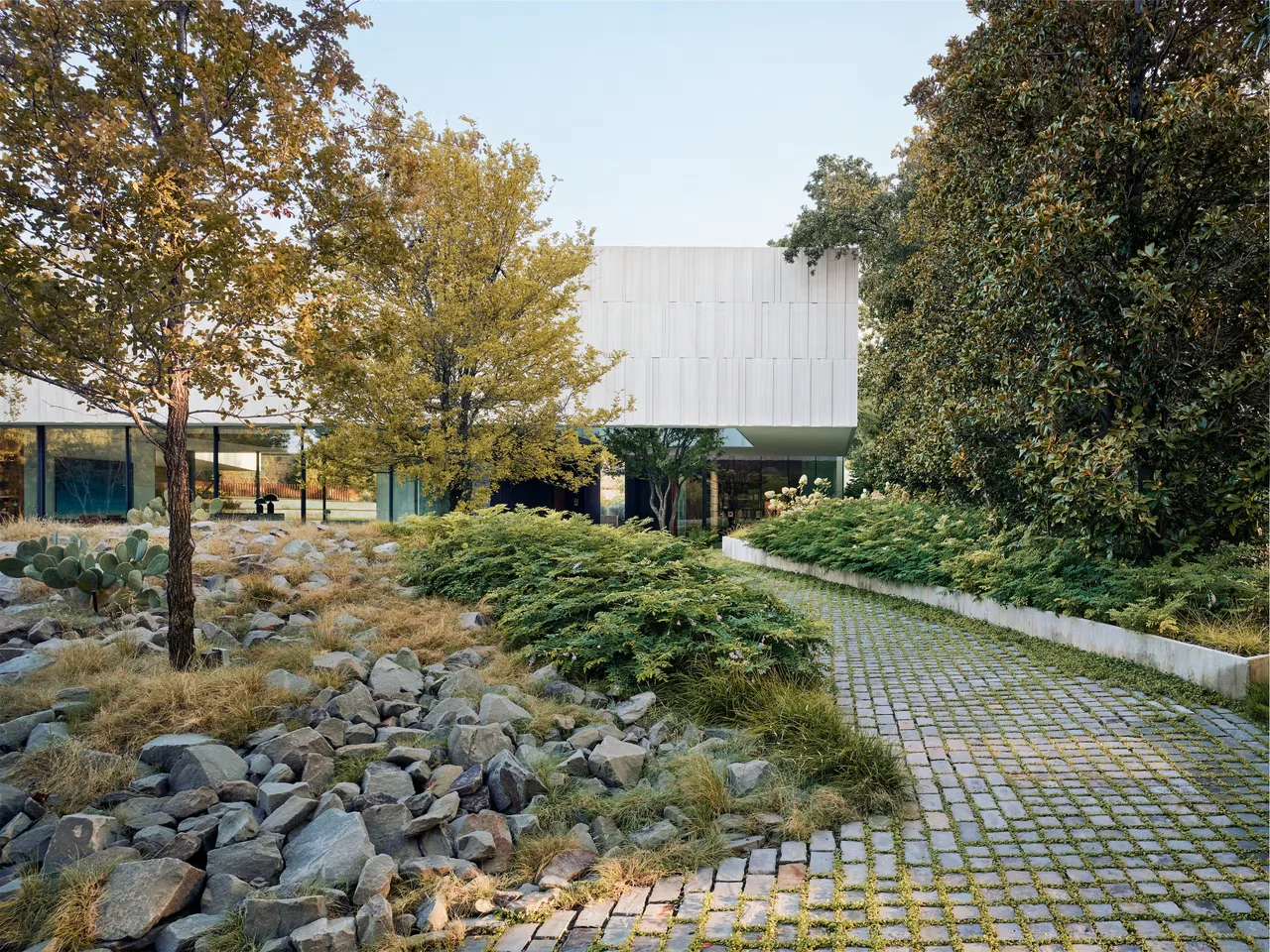 Highland Park Residence features a modern cantilevered design with a naturalistic stone and plant landscape in front.