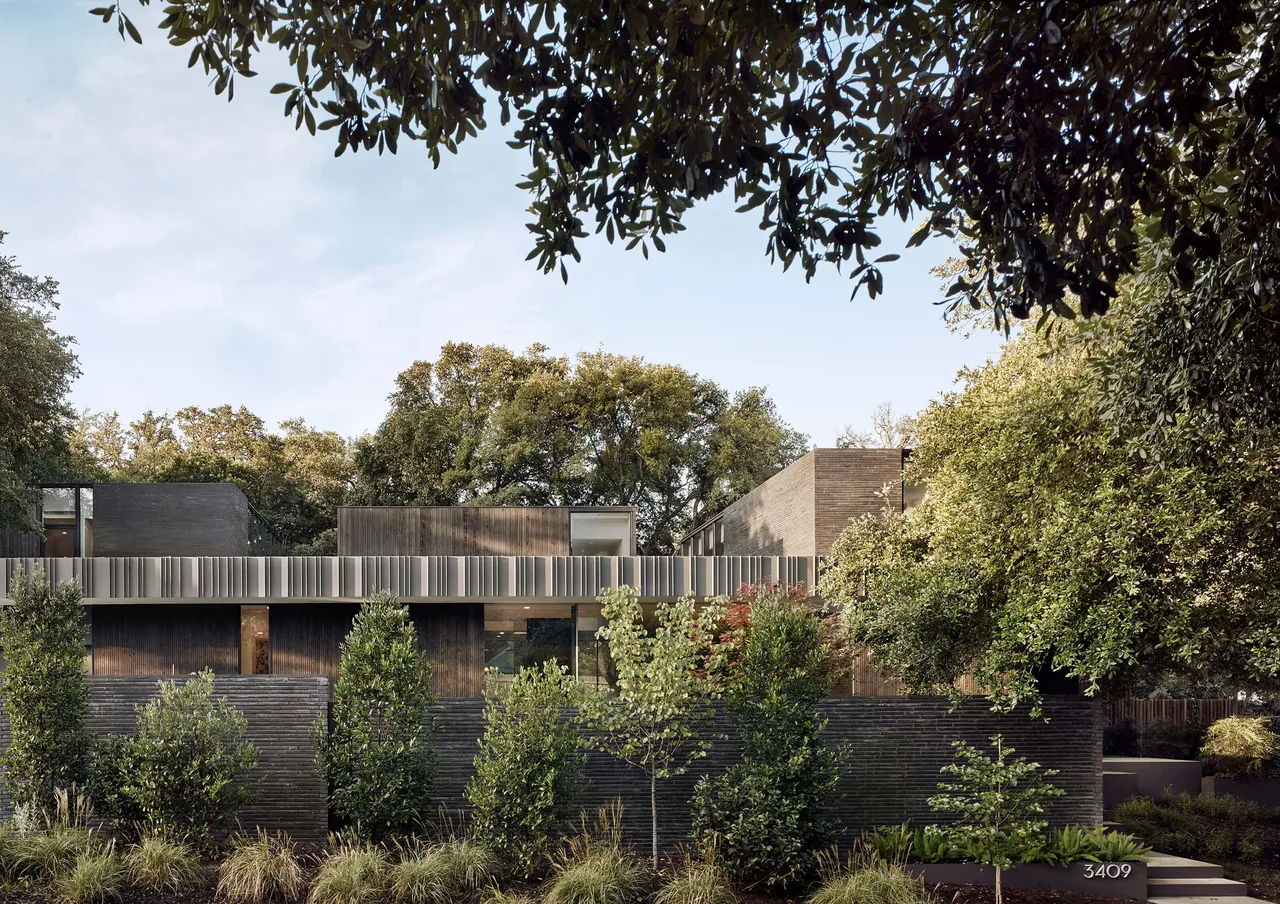 Exterior front view of the Tarrytown Residence showing black brick siding and lush landscaping.