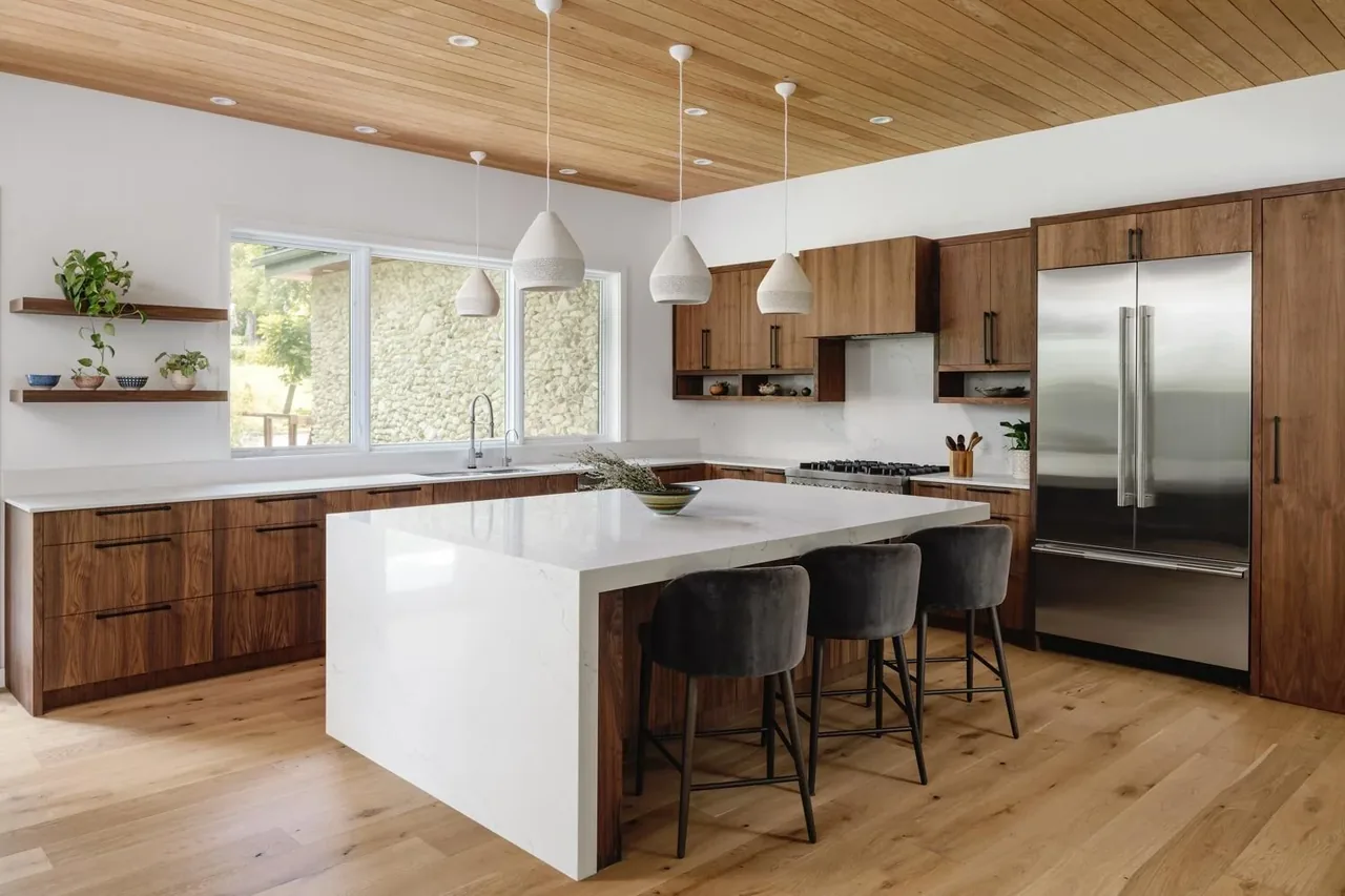 Kitchen features walnut cabinets, white quartz countertops, and stainless steel appliances under a wood-paneled ceiling.