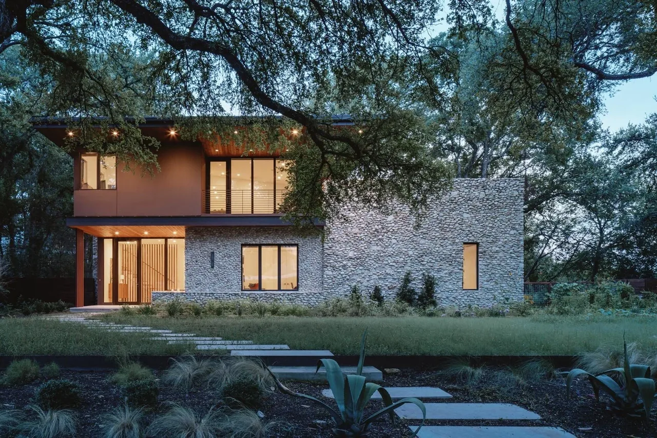 The Crestvale Residence by Clark | Richardson Architects features stone and stucco exterior walls with black window frames.