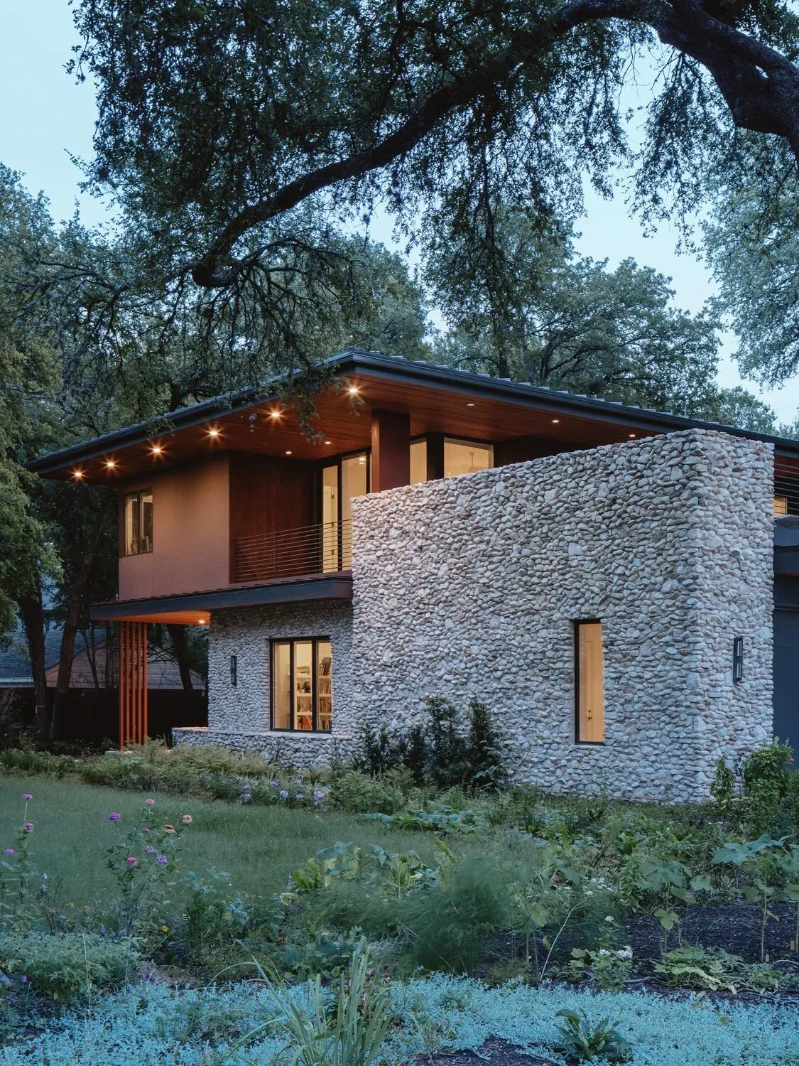 Crestvale Residence features a modern two-story design with prominent stone wall and wood ceiling details under an extended flat roof.