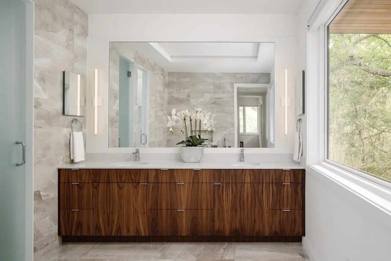 Crestvale residence bathroom features a large mirror and walnut double vanity with natural light from the window.