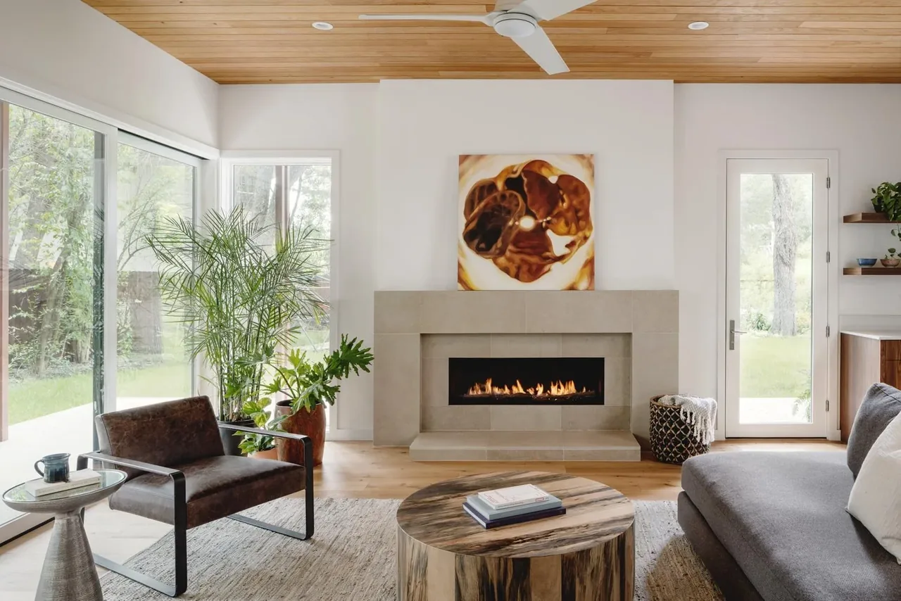 Crestvale residence living room features a stone fireplace, wood ceiling, and floor-to-ceiling glazing, designed by Clark | Richardson Architects.