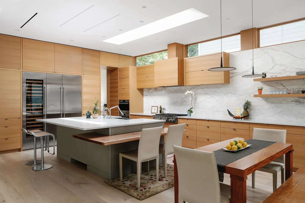 Kitchen of the Ramsey residence features wood-paneled cabinetry, a white island, and natural light from upper clerestory windows.