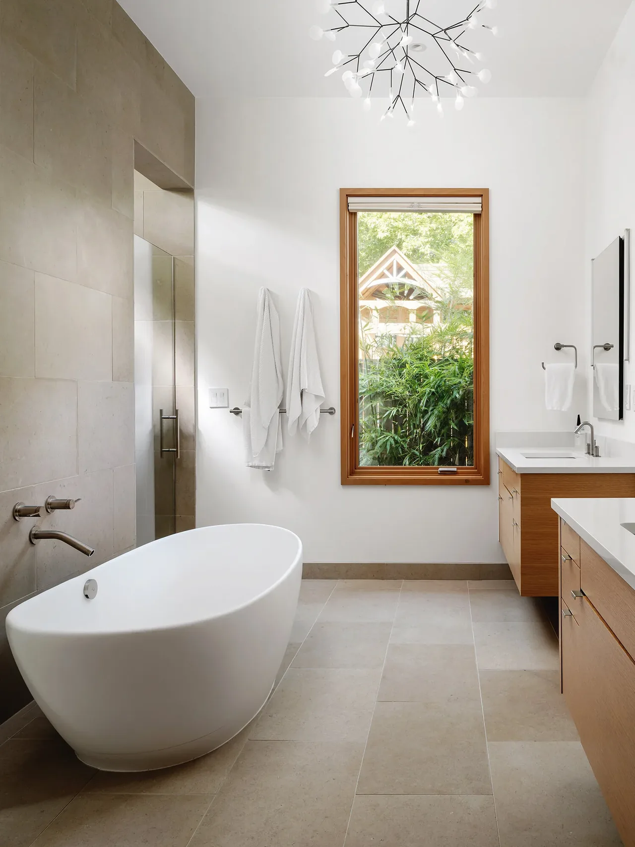 Modern bathroom with a freestanding tub, wood-framed window, and double vanity at Ramsey Residence by Clark | Richardson Architects.