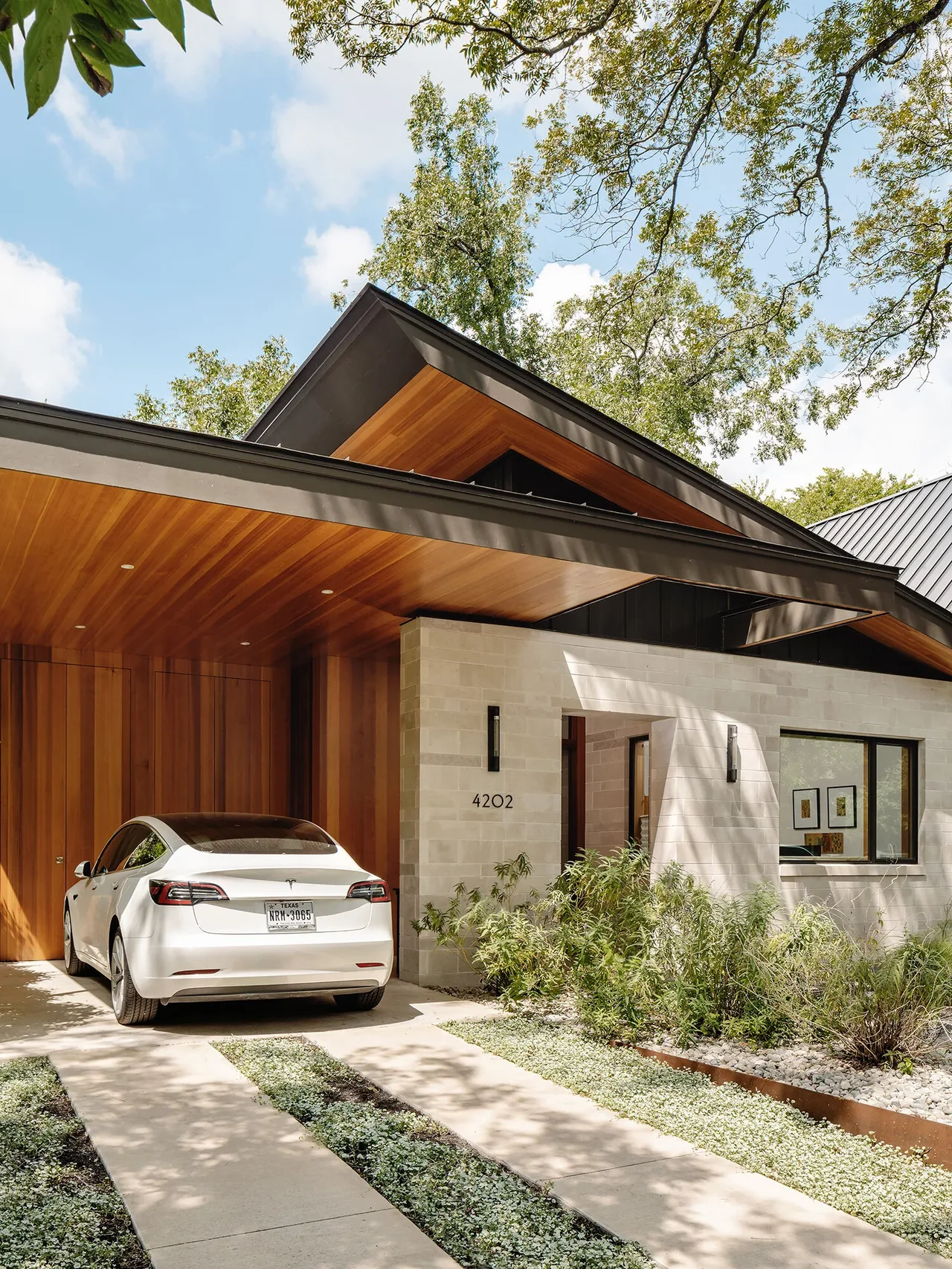 The Ramsey Residence features a modern design with a wood-paneled carport ceiling and concrete block walls.