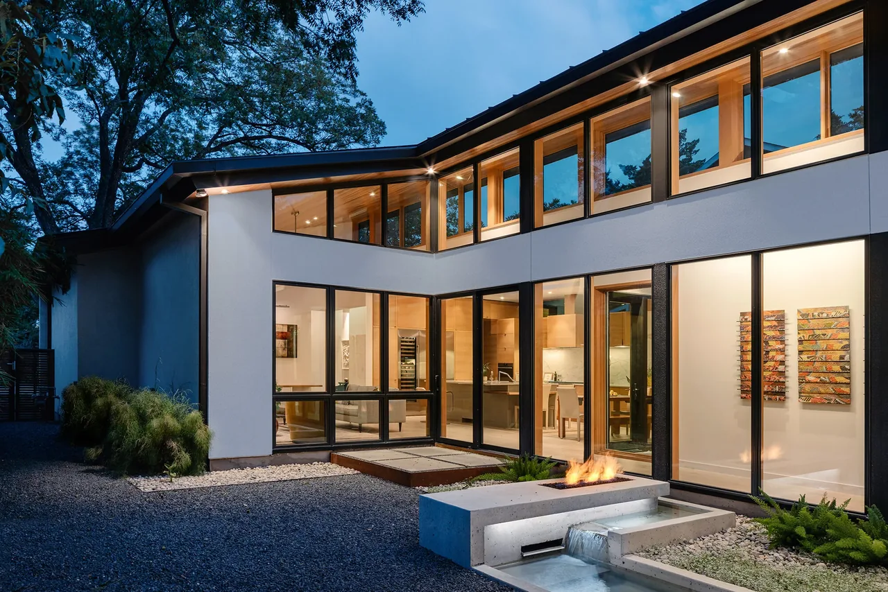Modern residence with large black-framed windows and a concrete fire feature outside, designed by Clark | Richardson Architects in Austin.