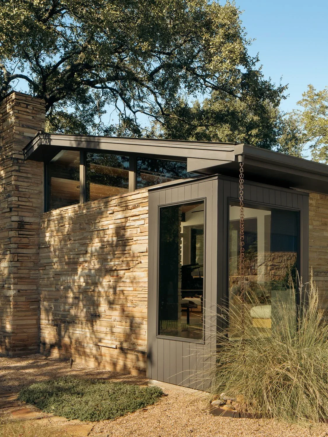 Stone wall and black-framed windows on a flat roofed section of the butterfly residence.