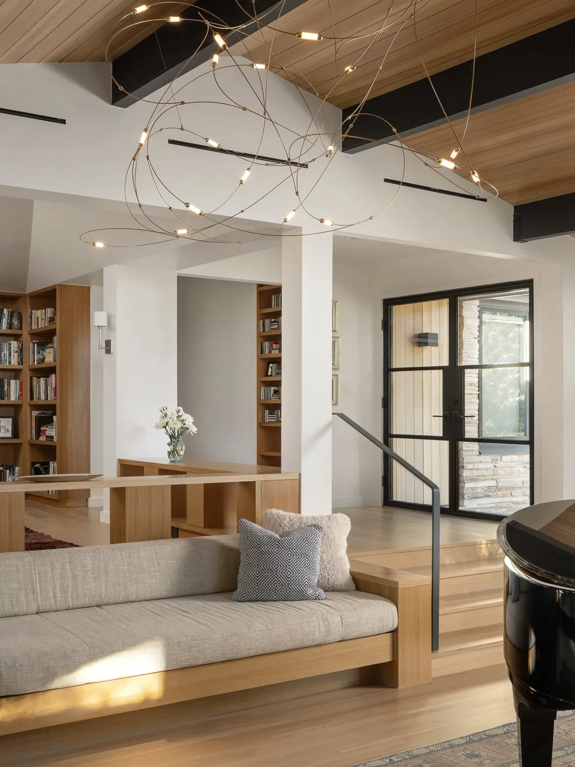 Living area with built-in wooden bench seating and modern lighting in the butterfly residence by Clark | Richardson Architects.
