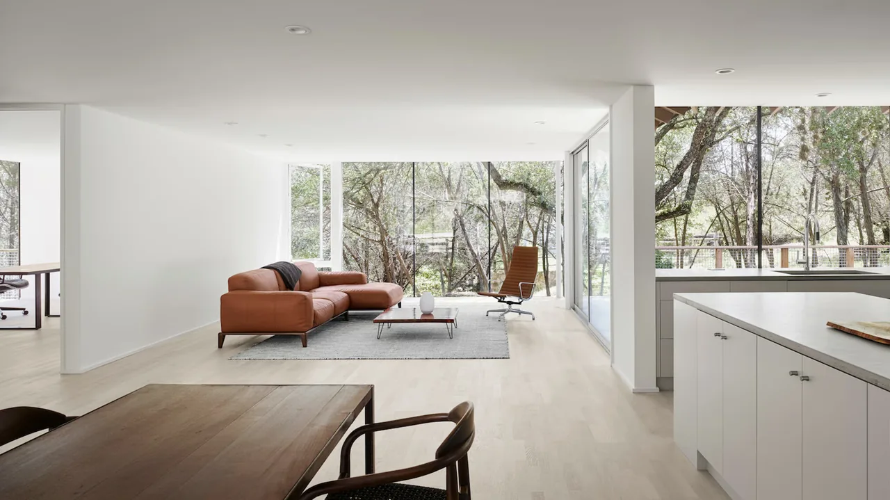 Living room with floor-to-ceiling windows and a contemporary seating area adjacent to the kitchen and dining space.