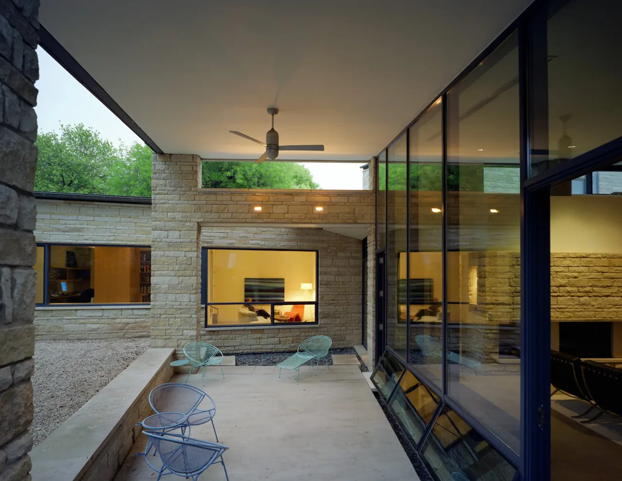 Covered patio with stone masonry and floor-to-ceiling glazing adjacent to the house living spaces.