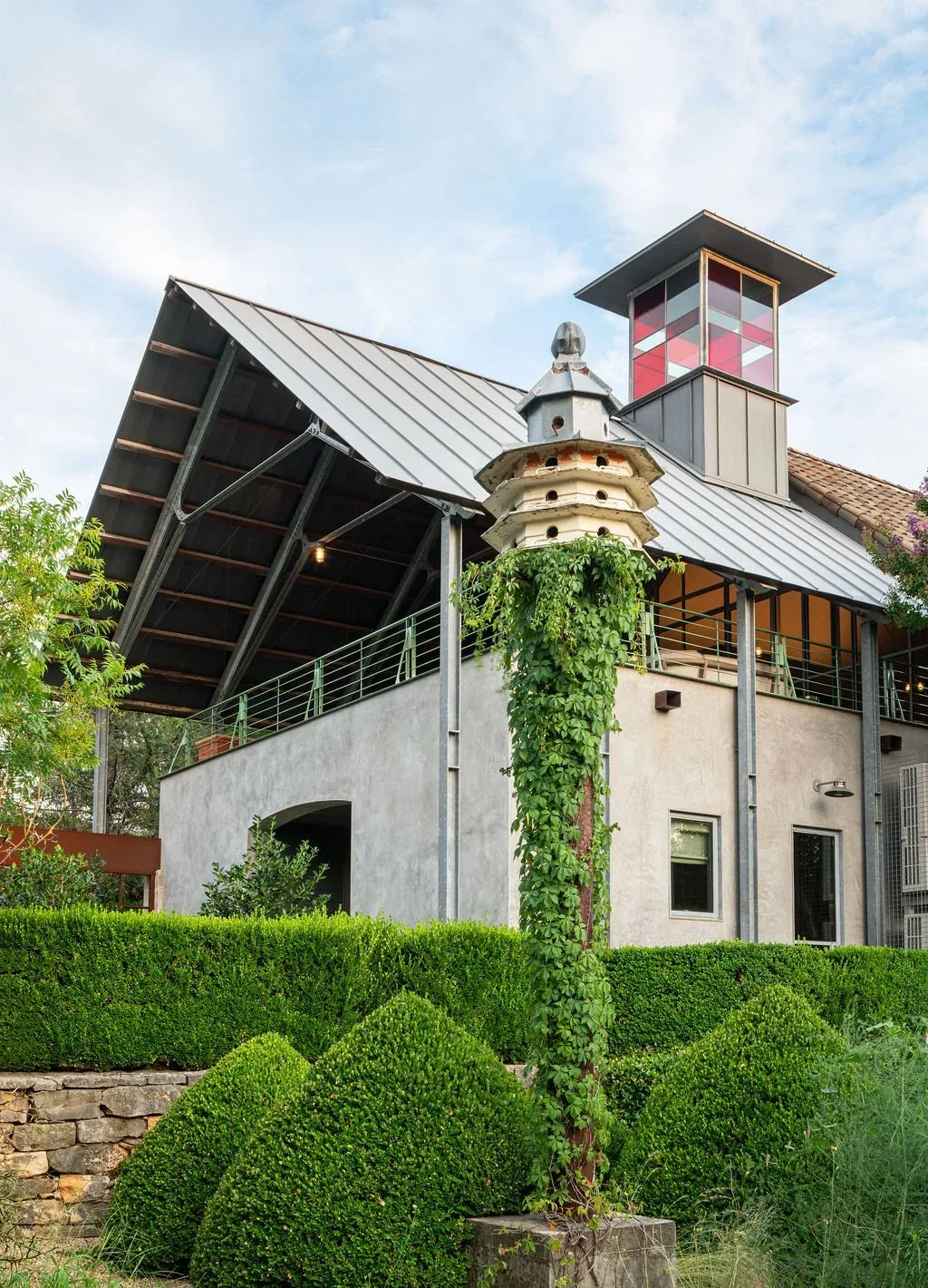 The Hassell Gallery features a metal sloped roof, an open upper-level covered patio, and a distinctive cupola with red glass panels.