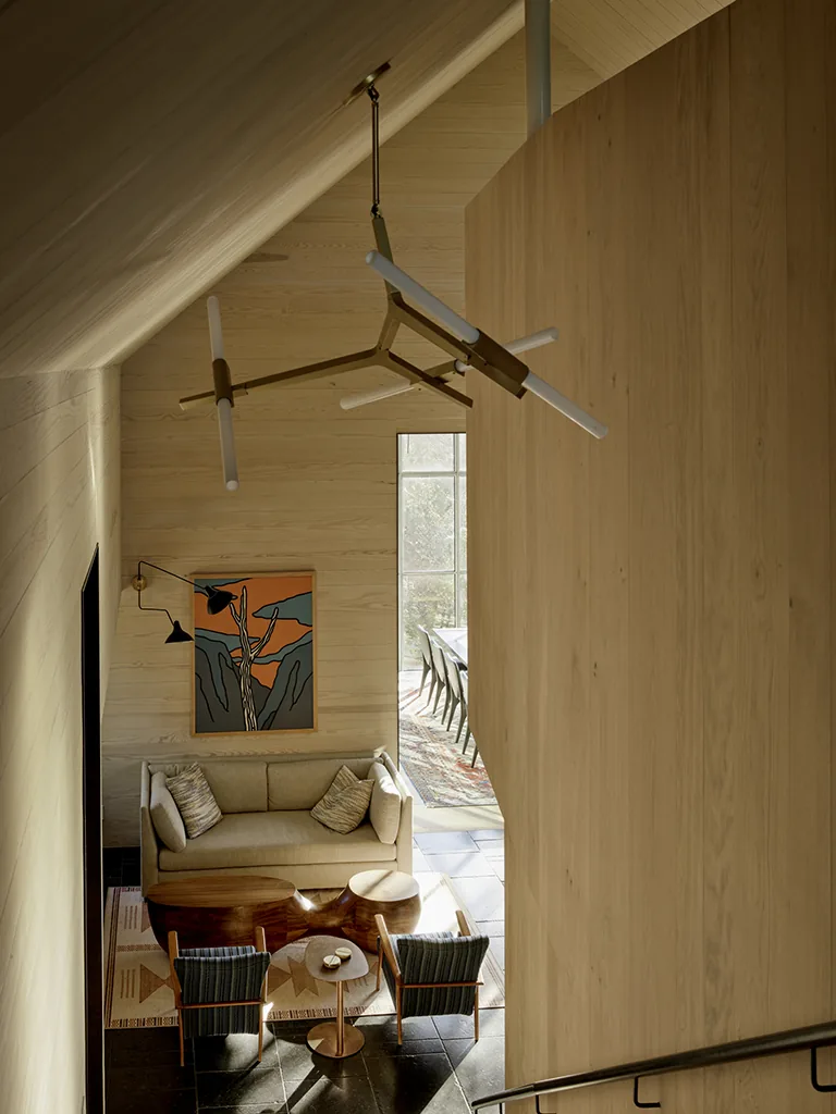 Living area features wood paneling, modern lighting, and natural light from a large window near the dining space.