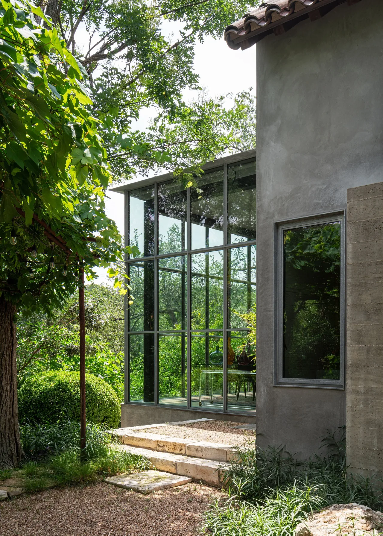 The Hassell Gallery features a glass sunroom with metal framed windows and a stucco exterior with clay roof tiles.