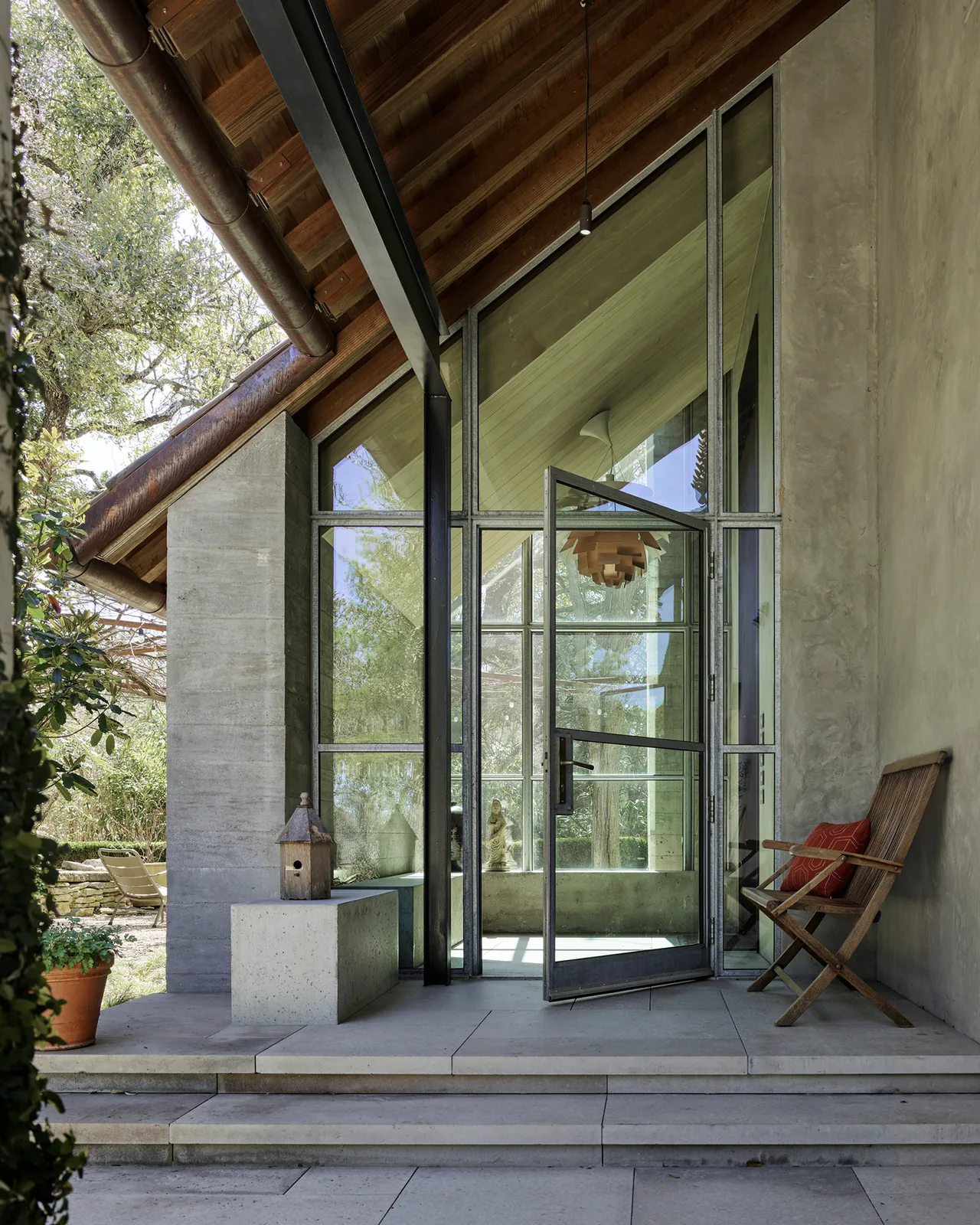The Hassell Gallery entry features a large glass pivot door and a sloped cedar ceiling over a concrete porch.