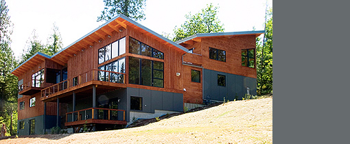 Hillside House by Silo Architecture + Design features wood siding and a multi level roof on a sloped site.
