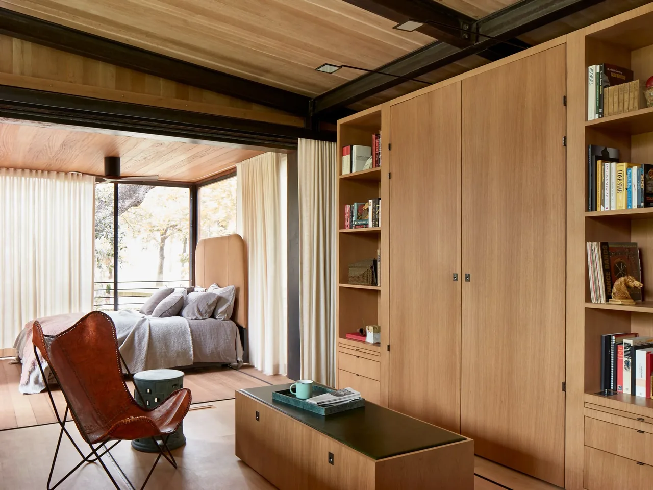 Jewell Box bedroom and living space feature wood paneling, large windows with sheer curtains, and minimalist furnishings.