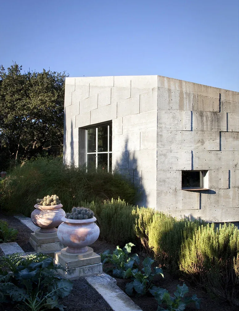 The Concrete Studio Gallery features a textured concrete exterior wall with windows and lush garden plantings.