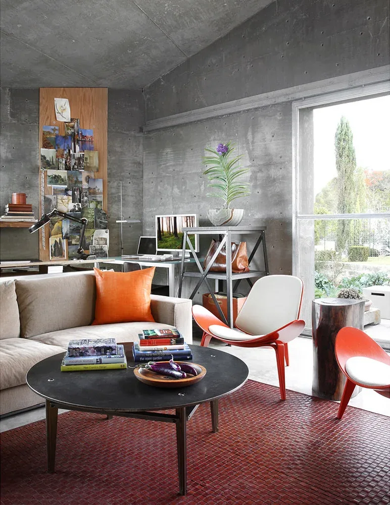 Concrete Studio Gallery living space features textured concrete walls and a small rectangular window with outdoor greenery visible.