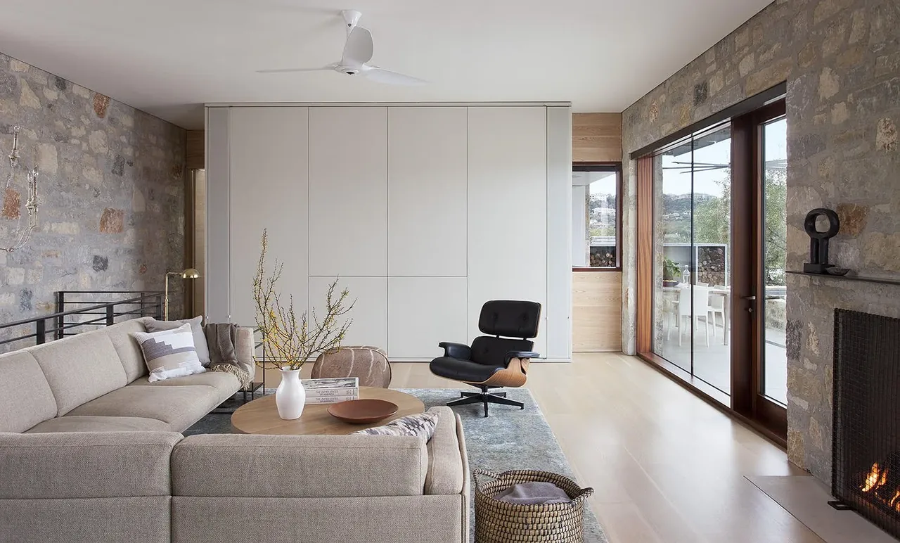 Living room features stone walls, floor-to-ceiling sliding glass doors, and a modern fireplace with firewood storage.
