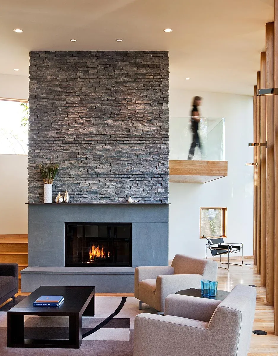 Living room features a tall stacked stone fireplace with gray hearth and beige armchairs.