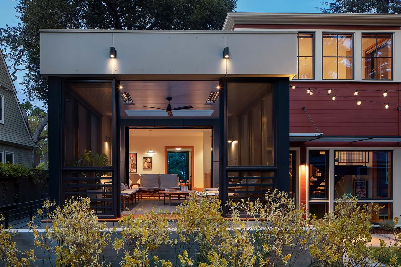The Red Lady project features black window frames, a screened porch, and modern exterior lighting.