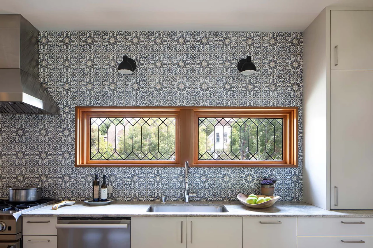 Kitchen with patterned tile backsplash and two wood-framed leaded glass windows above the sink.