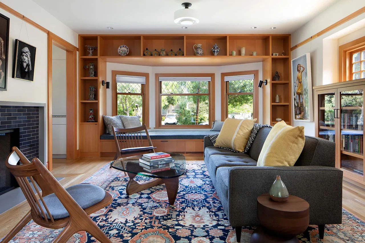 Bright living room featuring a bay window, built-in wood shelving, and mid-century modern furniture.