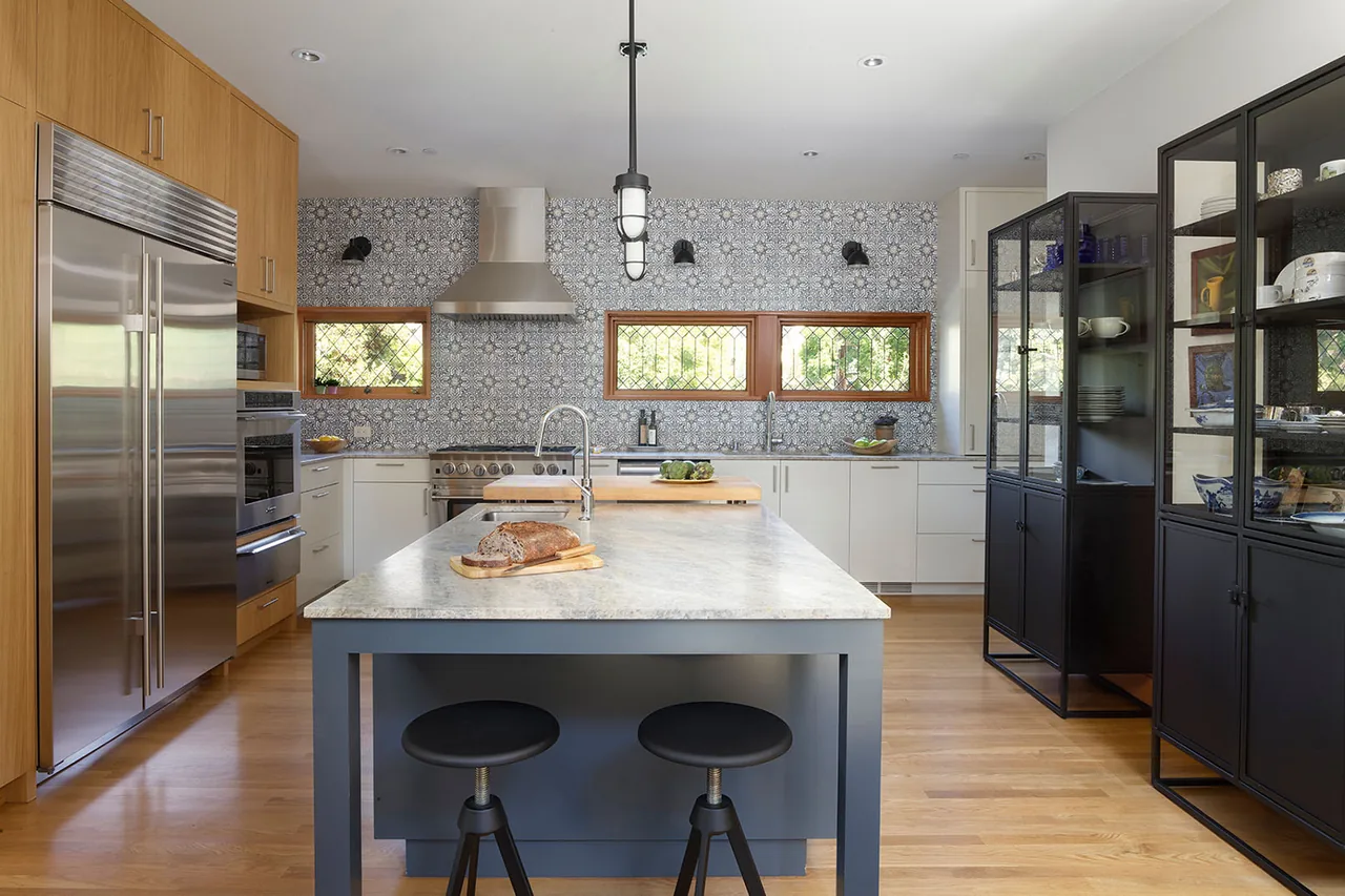 Kitchen featuring a central island with bar stools, patterned tile backsplash, and wood cabinetry.