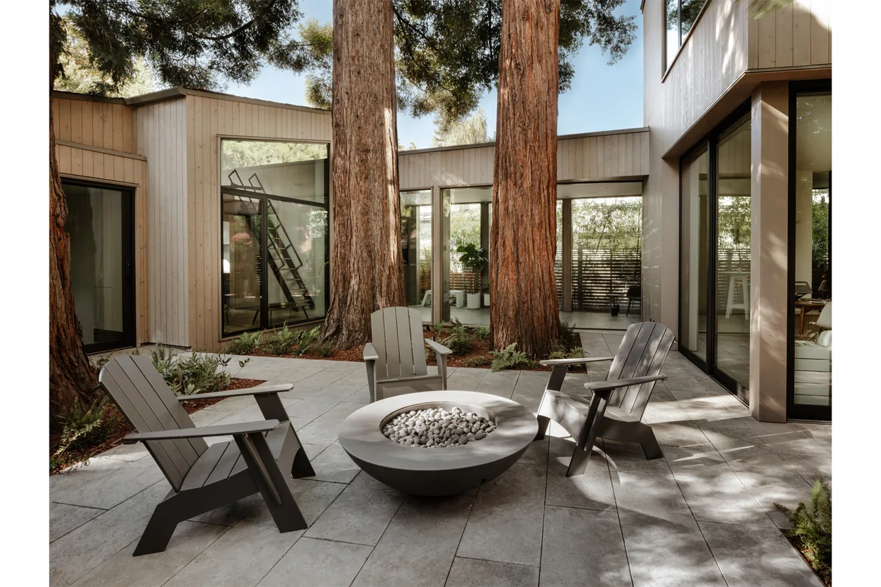 The courtyard patio at eight tree eight features a fire pit surrounded by Adirondack chairs and mature trees.