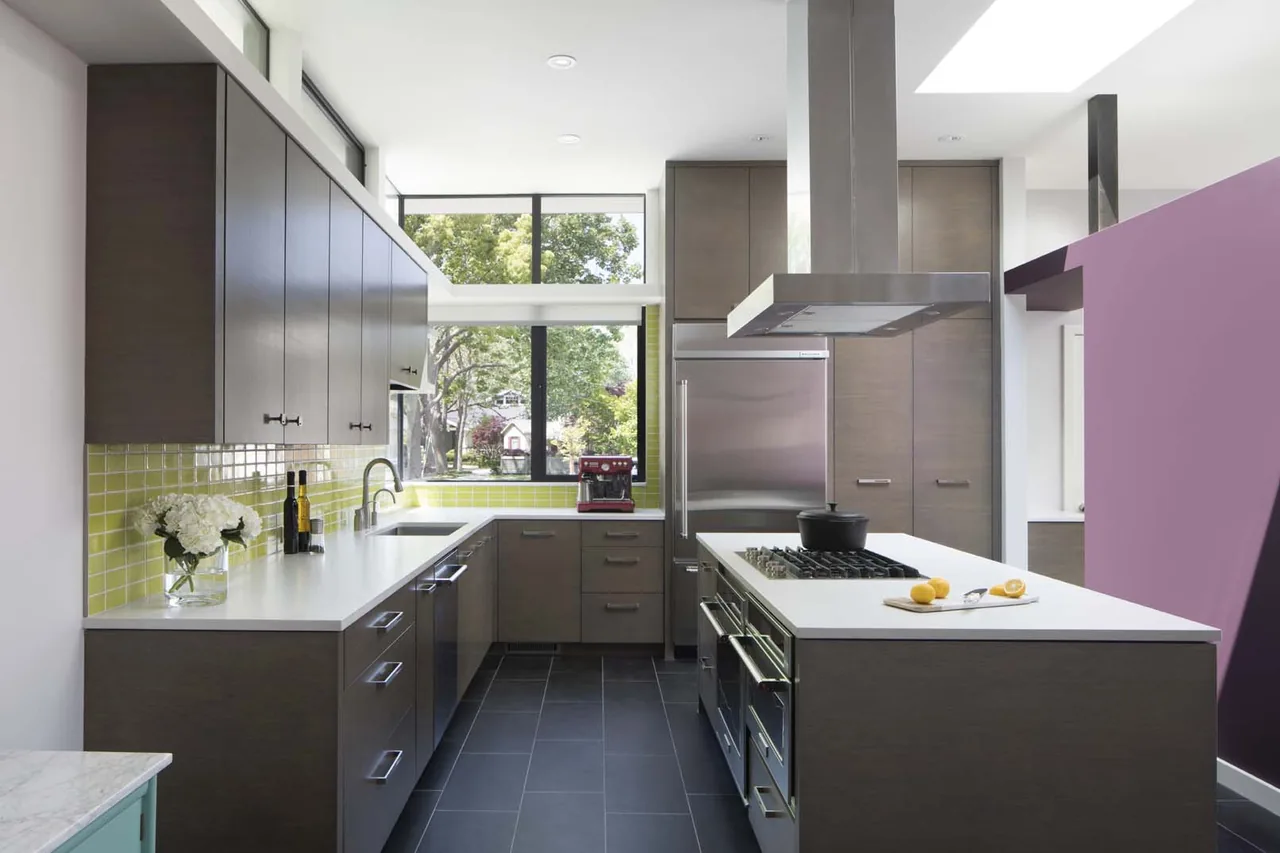 The kitchen in the Moto House features dark cabinetry with a yellow tile backsplash and stainless steel appliances.