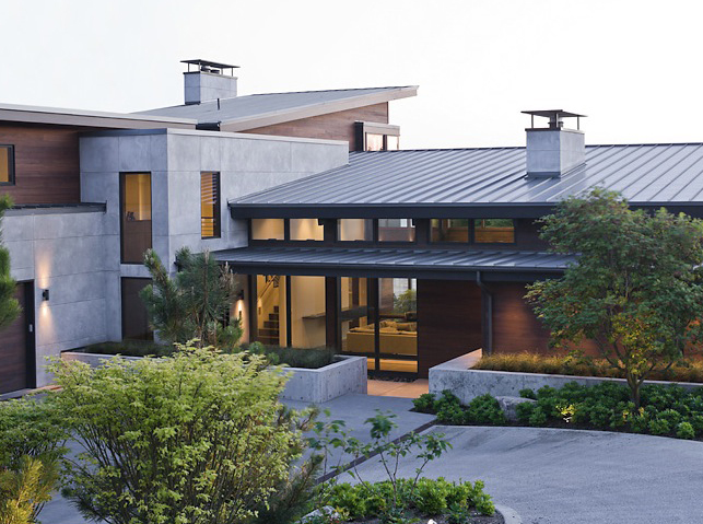 The Porter Residence features a combination of concrete and wood siding with a standing seam metal roof and landscaped entrance.