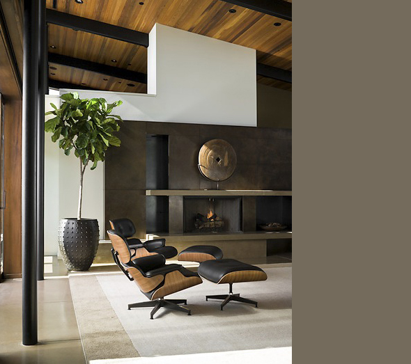 Living room in the Porter Residence features a wood-paneled ceiling and a modern black leather lounge chair by the fireplace.