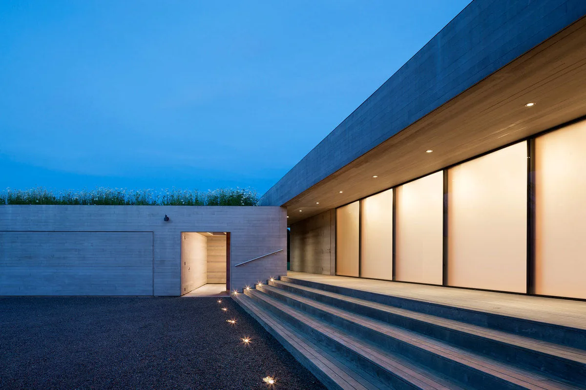 The Watermill Residence features a linear facade with broad steps and recessed lights under an extended roof overhang.