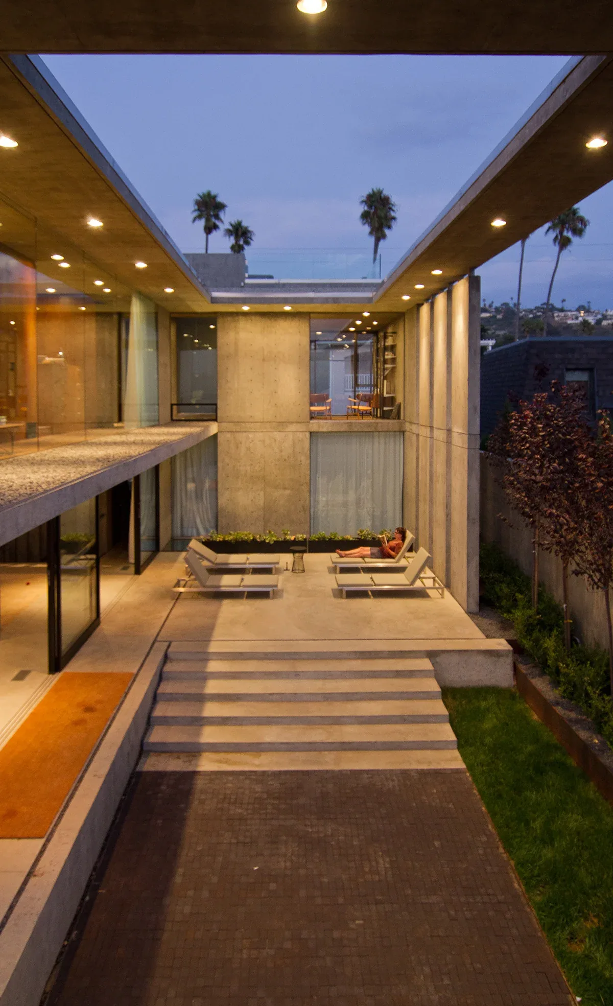 The Cresta features a concrete courtyard with integrated recessed lighting and floor-to-ceiling glass walls.