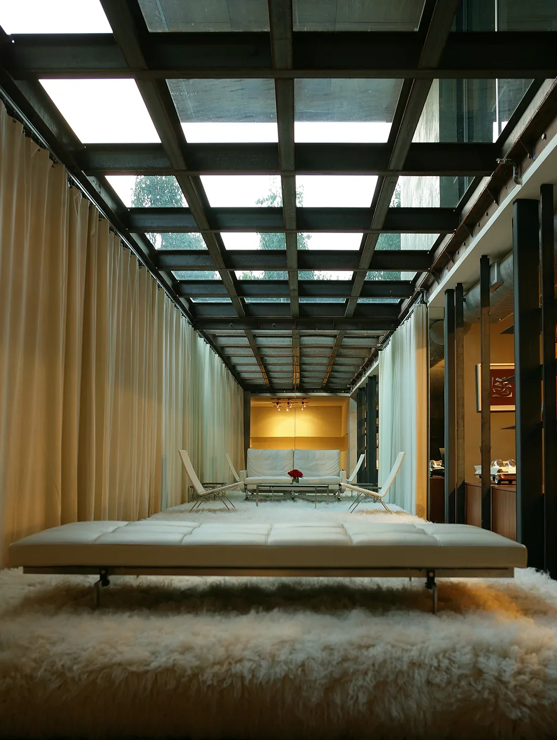Interior lounge space with modern white seating beneath a steel-framed glass ceiling in The Prospect by Jonathan Segal.
