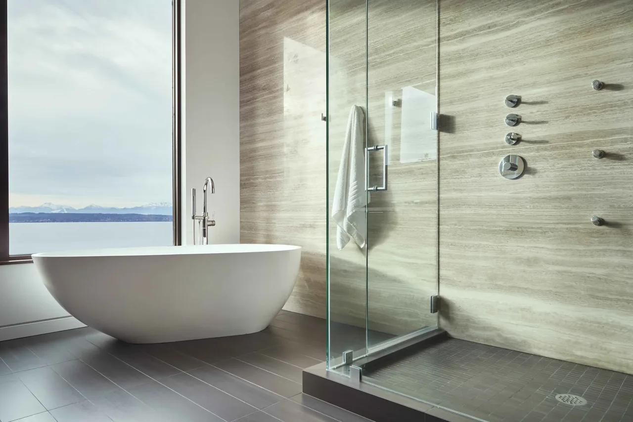 Modern bathroom with freestanding tub next to a large window and a glass-enclosed walk-in shower.